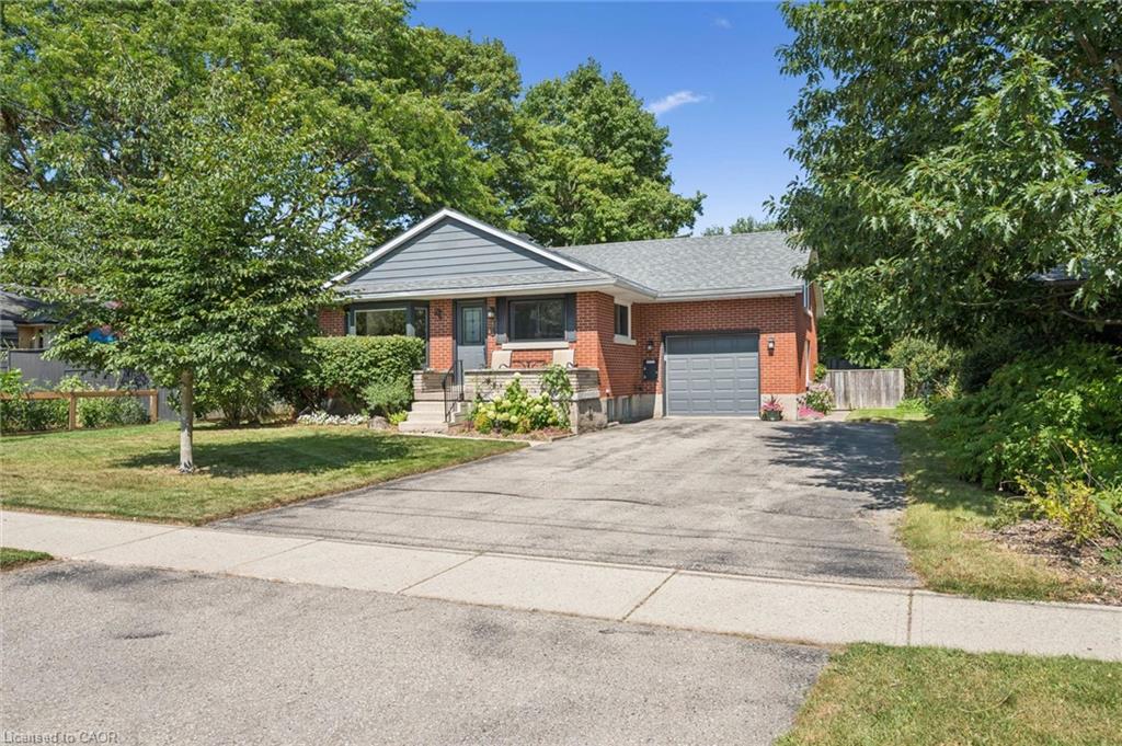Brick exterior with gray siding, attached garage, paved driveway, and established landscaping