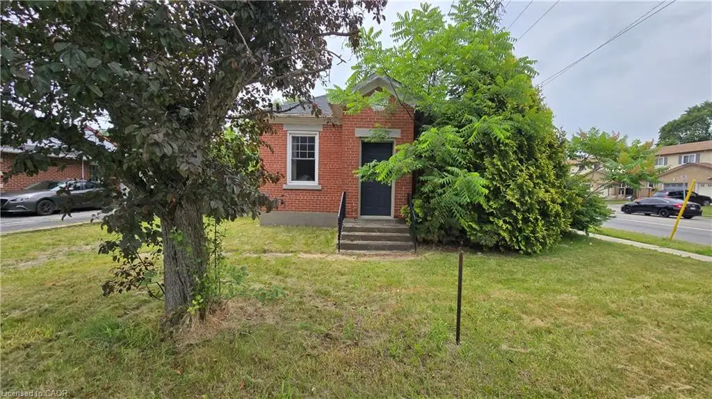 Red brick exterior featuring a dark entrance door, white window trim, and front steps with a black metal handrail