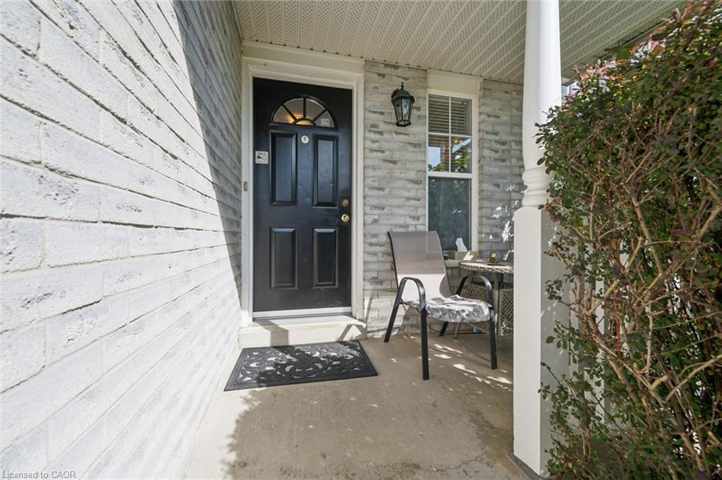 Inviting front porch featuring a paneled entry door with transom window, a decorative wall-mounted lantern, and a classic white column
