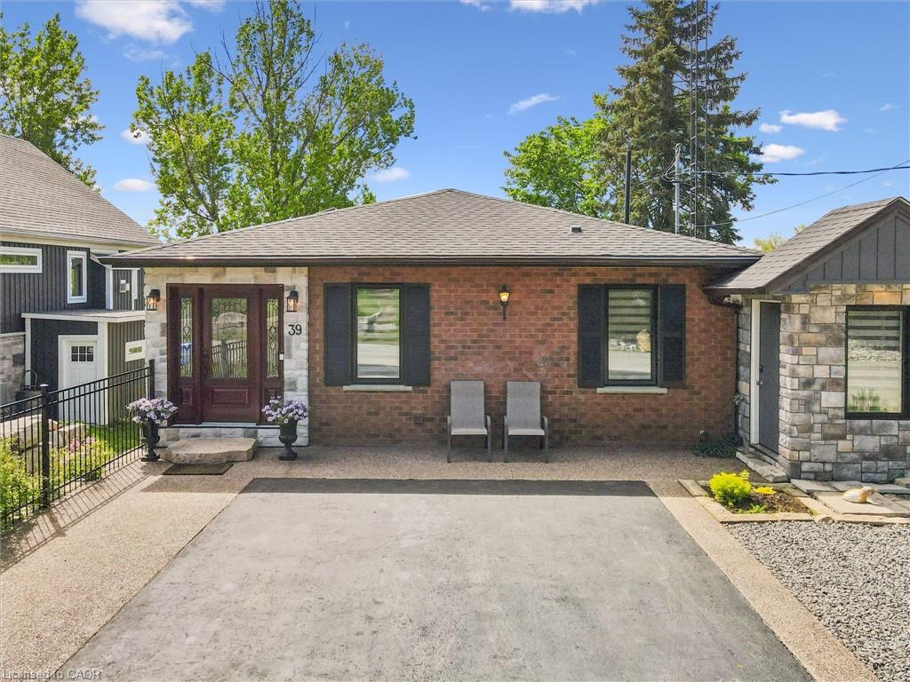 Brick and stone facade featuring a dark wood-finish entry door with decorative glass inserts, flanking stone columns, and exterior lighting