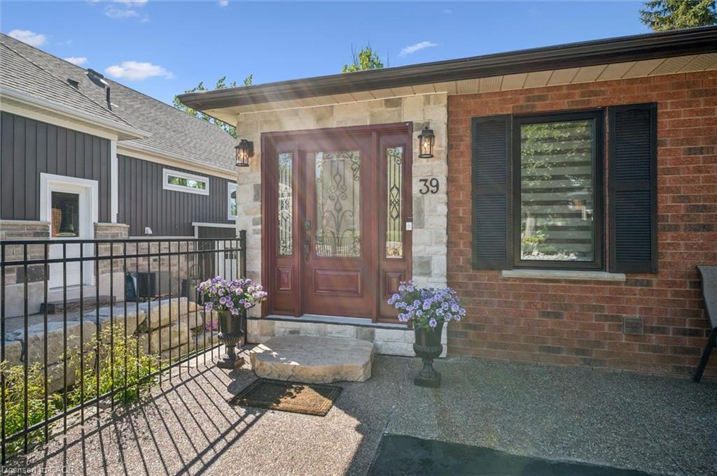 Red brick and stone facade featuring a decorative wood entry door with glass inserts, flanked by exterior lighting fixtures