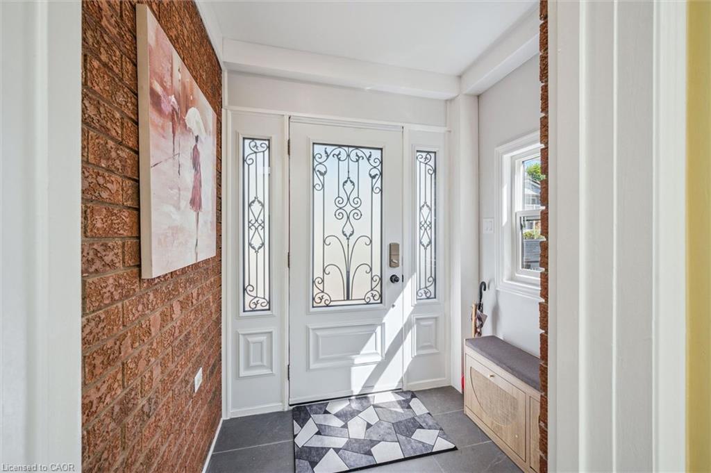 Entryway featuring a white paneled door with decorative wrought iron glass inserts, flanking sidelights, and a transom window