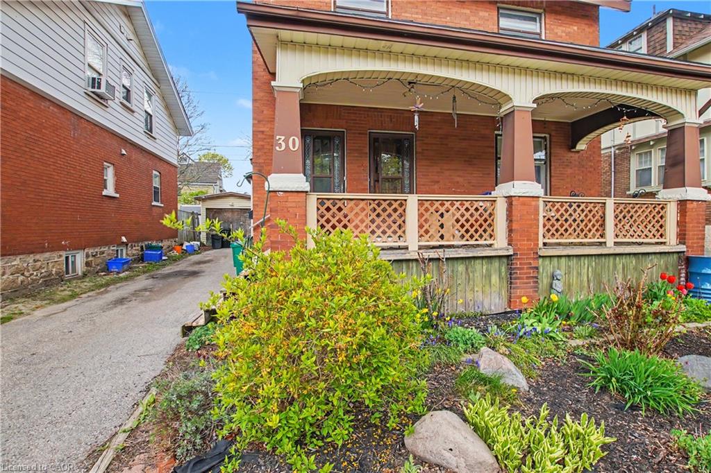 Brick facade featuring a covered front porch with arched details and decorative lattice railing