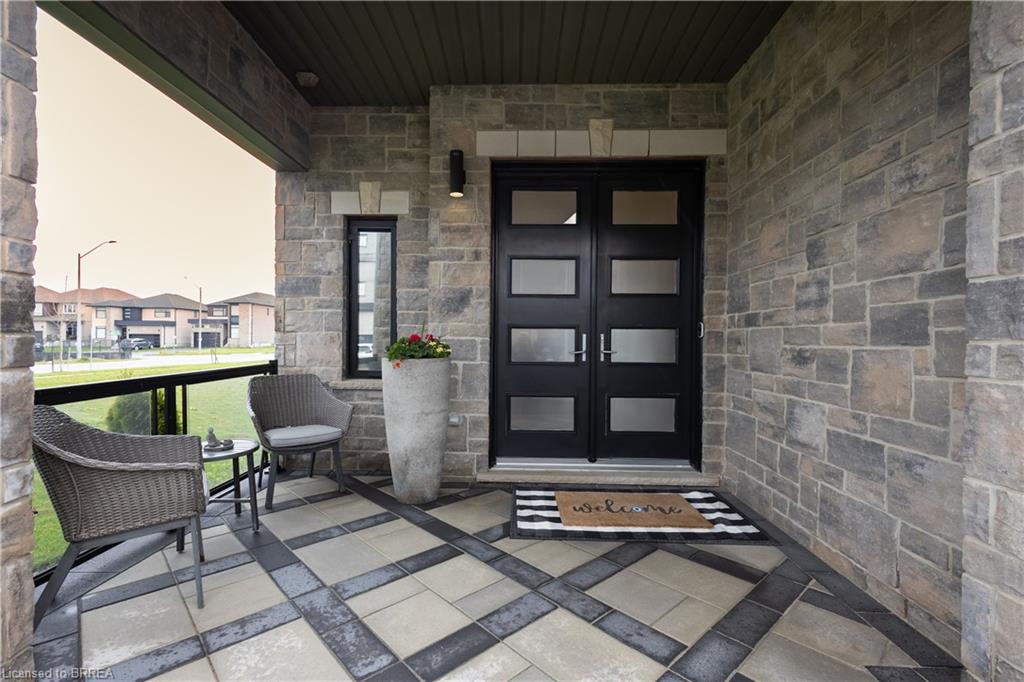 Stone facade entry featuring double doors with frosted glass inserts, a single vertical window, and a dark soffit