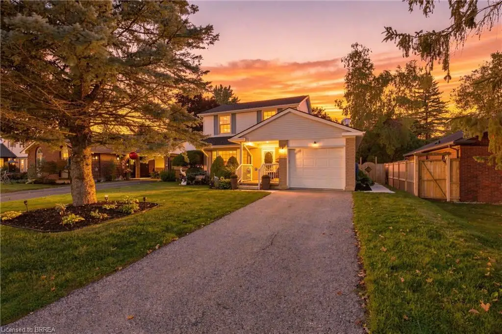 Two-story dwelling with an attached garage, paved driveway, and mature landscaping
