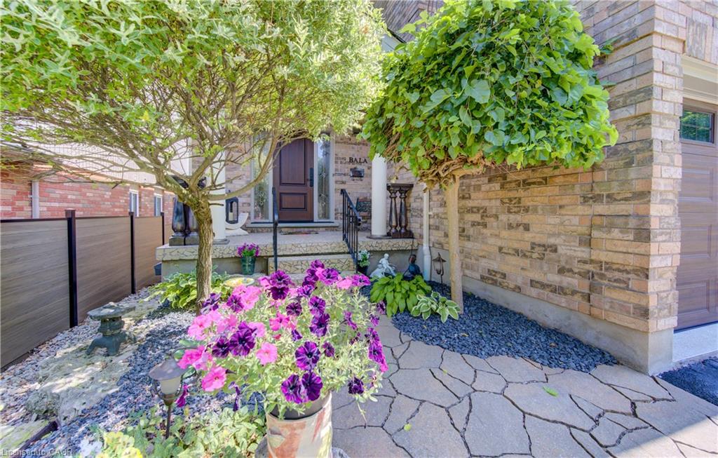 Front entrance featuring a paneled wood door, stone porch, wrought iron railings, and a flagstone walkway