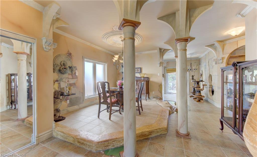 Interior space featuring decorative columns, arched doorways, a coffered ceiling, tiled flooring, and a built-in wall niche with architectural detailing