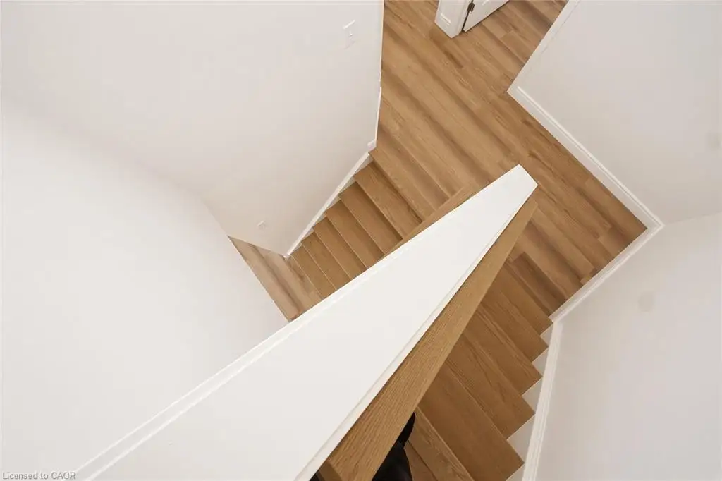 Wood-finish flooring with white trim and a contrasting white and wood-finish stair railing