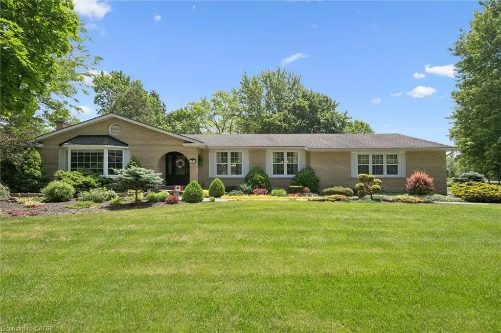 Ranch-style residence featuring a light brick exterior and a dark shingle roof
