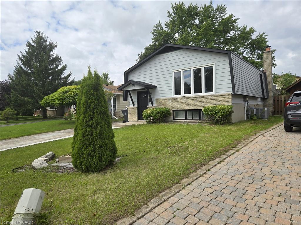 Split-level residence featuring light gray siding, a stone facade, and a dark asphalt roof