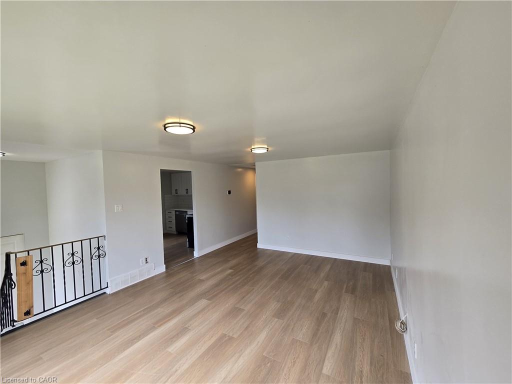 Wood-finish flooring throughout, complemented by a decorative iron railing and recessed lighting fixtures