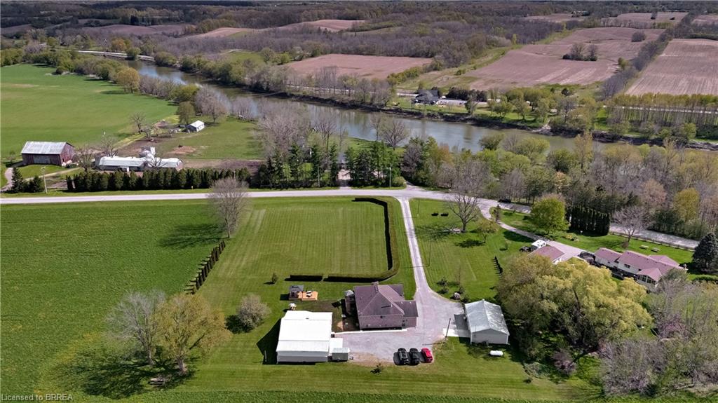 Aerial view showcasing the property's expansive grounds, a paved driveway, and surrounding green fields