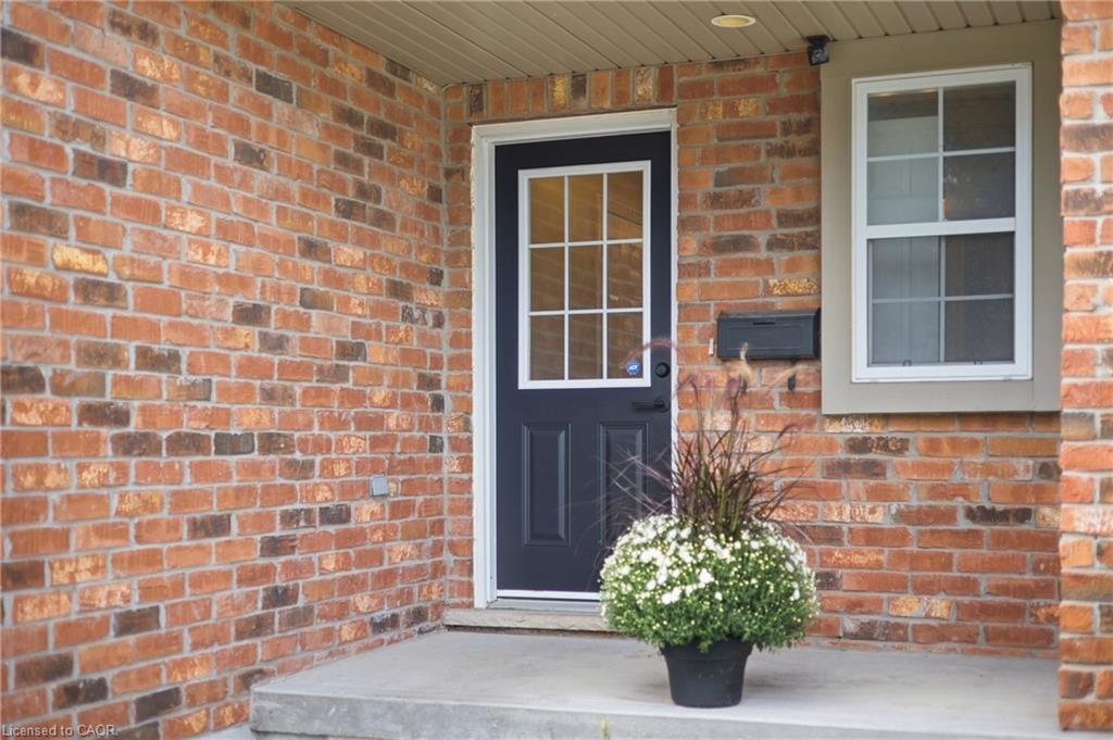 Brick exterior with a dark-paneled entry door, white window trim, and a concrete porch