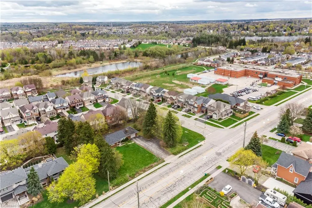 Aerial perspective showcasing a residential neighborhood with diverse architectural styles, a nearby educational facility, and substantial green spaces