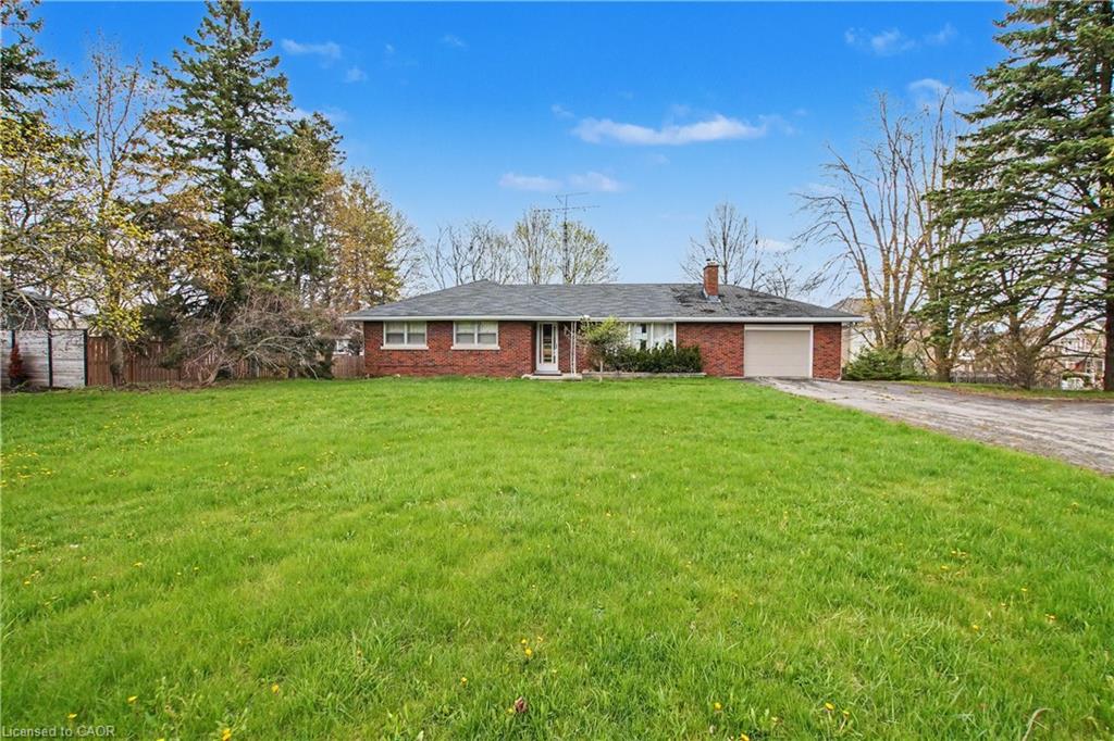 Expansive front lawn with mature trees and a long gravel driveway