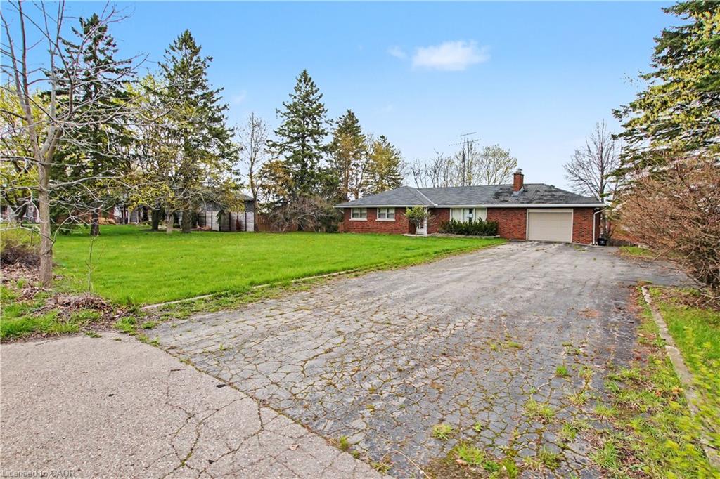 Brick ranch home featuring a single garage, dark shingle roof, and a prominent chimney