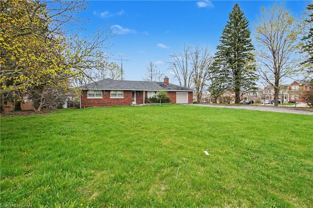 Expansive front lawn with mature trees and a brick single-story residence