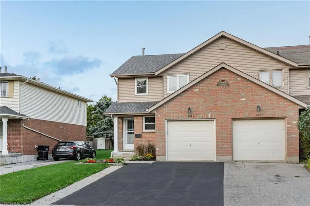 Brick and siding exterior with dual garage doors, a covered entry, and a paved driveway