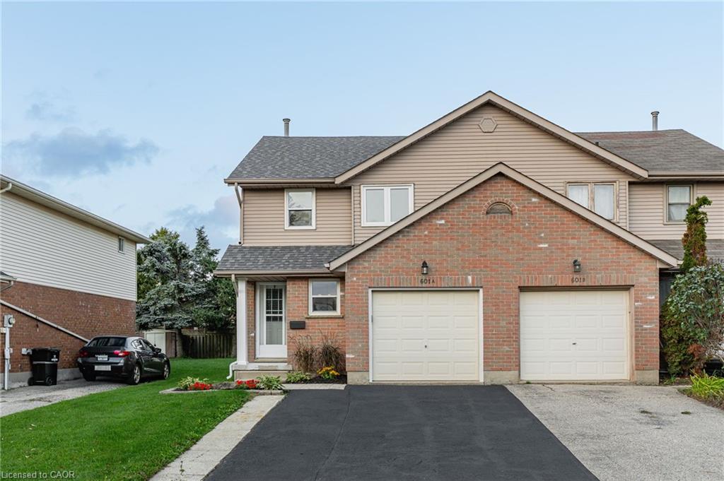 Two-story residence featuring brick and siding exterior, an attached garage, and a paved driveway
