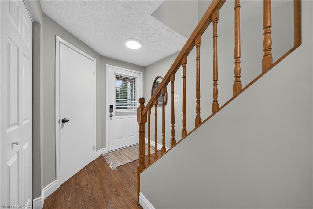 Wood-finish flooring, white paneled doors, and a wood staircase with turned spindles