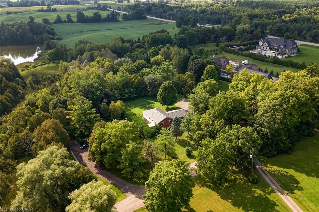 Expansive property featuring a red-sided home with a gray roof, surrounded by mature trees