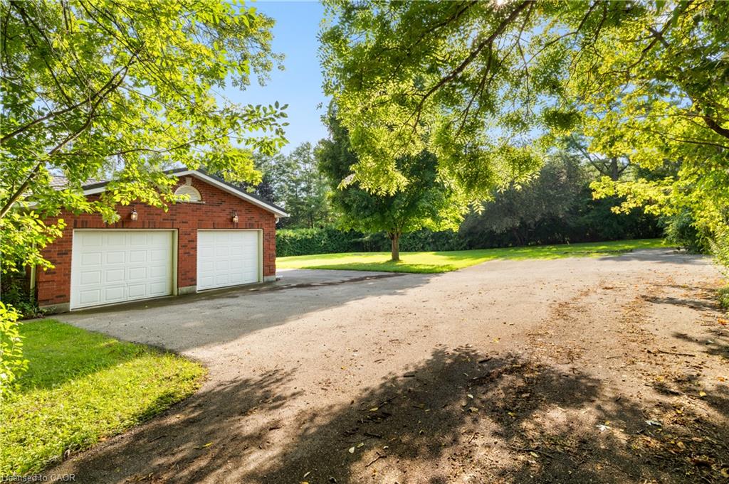 Red brick two-car garage with white paneled garage doors, exterior wall sconces, and a decorative arch accent
