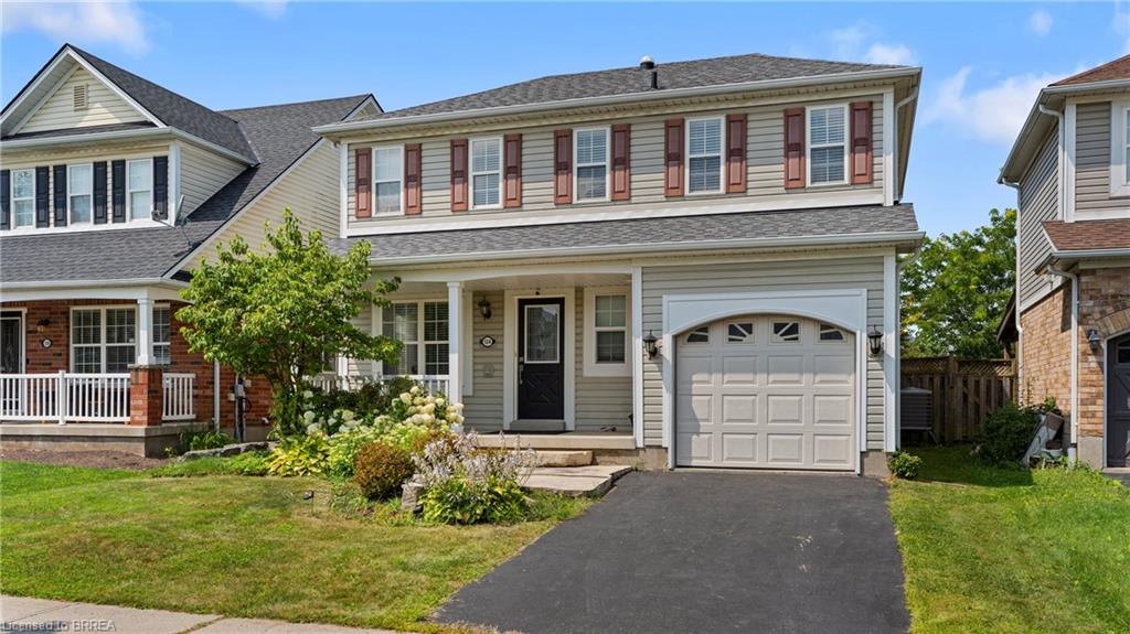 Two-story residence featuring siding exterior, a front porch, an attached garage, and a paved driveway