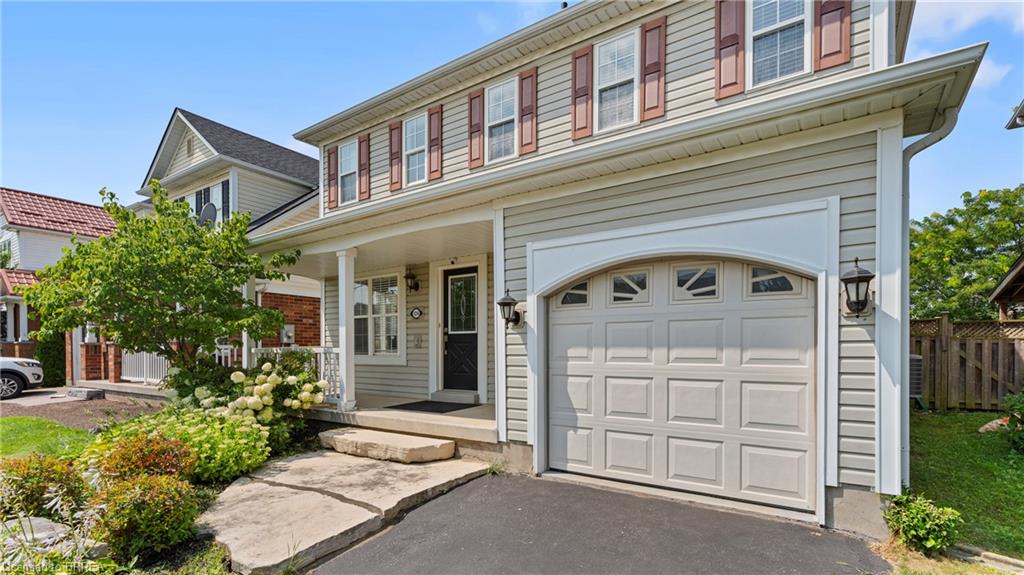 Two-story exterior with light-colored siding, a covered front porch, and an attached garage with an arched detail