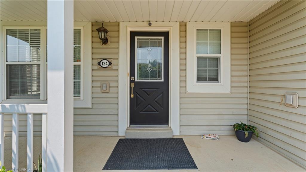 Covered front porch with a paneled black entry door featuring a decorative glass insert, complemented by an exterior wall sconce