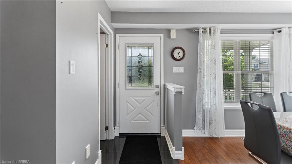 Entry door with decorative glass insert, wood-finish flooring, and white trim