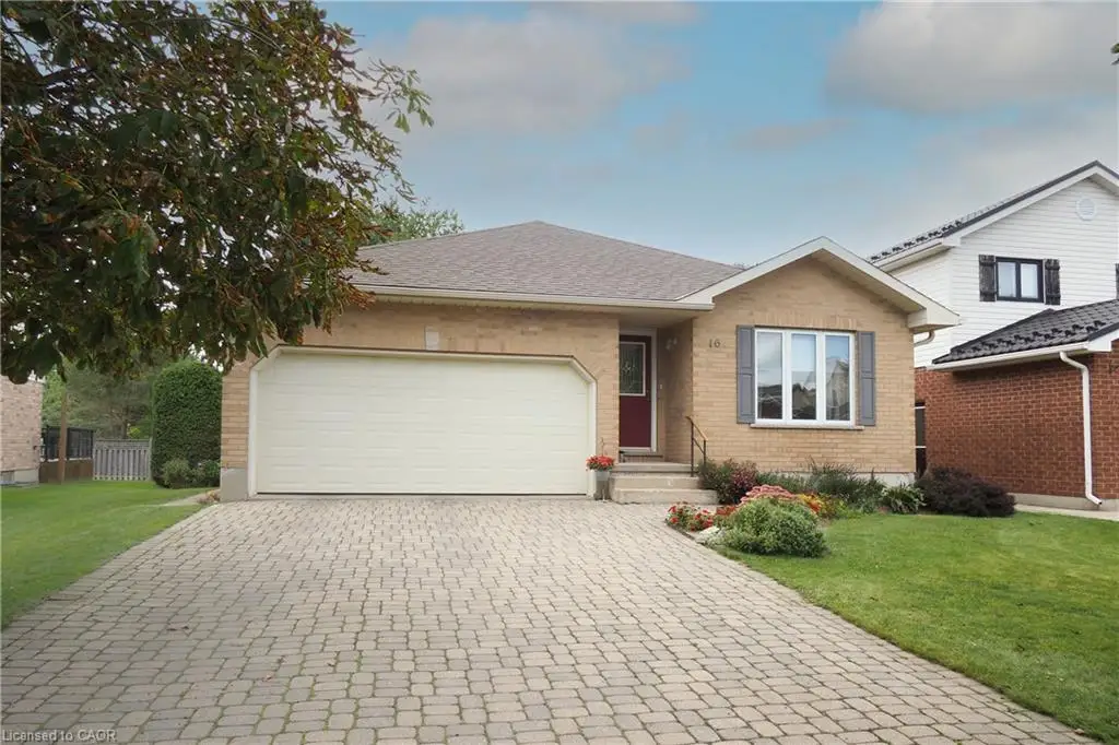 Brick exterior with a gabled roofline, featuring a paver driveway, an attached garage, and a landscaped front yard