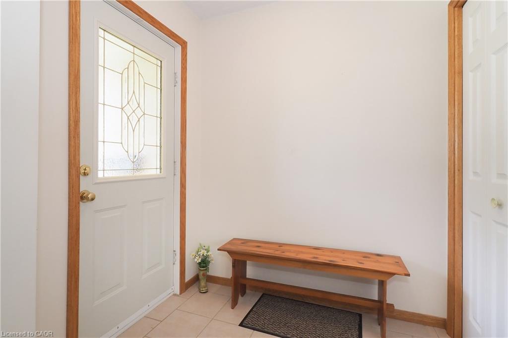 Entryway featuring a white insulated door with decorative glass paneling, stained oak trim, and neutral tile flooring