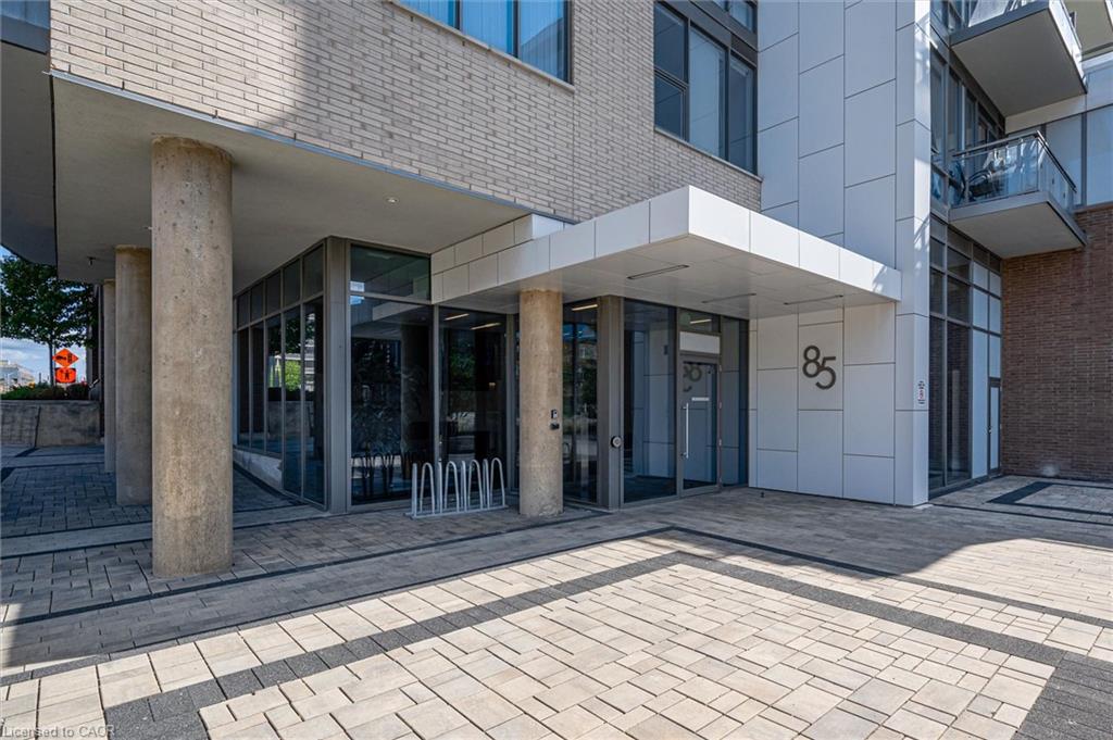 Contemporary building entrance featuring a prominent awning, large format numerical address, and a mix of brick and panel siding
