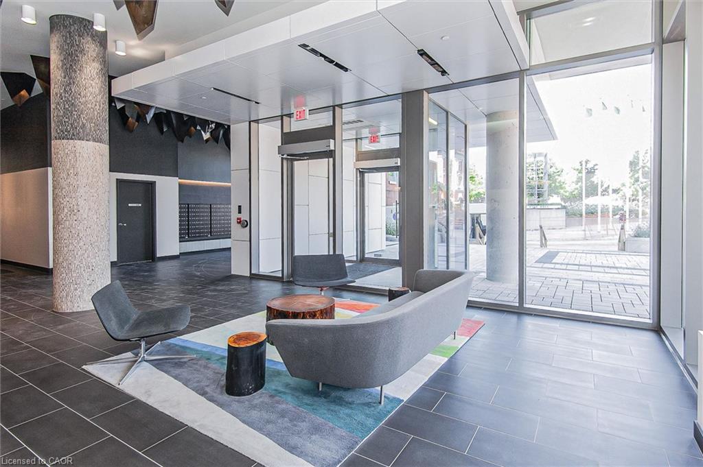 Building lobby featuring expansive floor-to-ceiling windows, dark tile flooring, a textured architectural column, and a modern ceiling design with integrated lighting