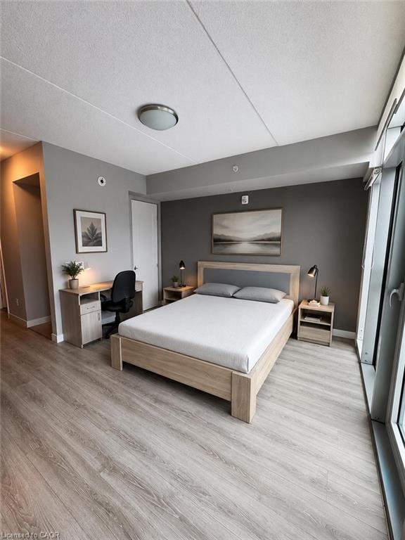 Bedroom featuring light wood-finish flooring, a contemporary ceiling light fixture, and a neutral color palette