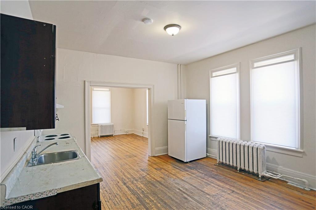 Wood-finish flooring throughout, white walls, and a built-in kitchen counter with sink and stovetop