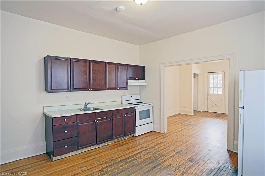 Kitchen featuring dark wood-finish cabinetry, light-colored countertops, and hardwood flooring
