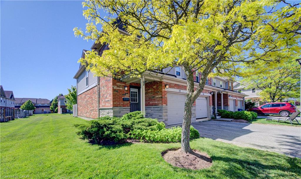 Brick and siding exterior, attached garage, covered entryway, and mature landscaping