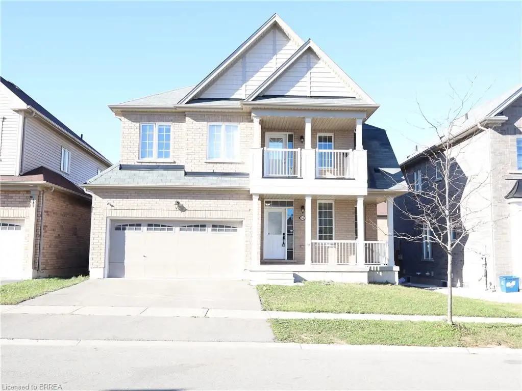 Two-story masonry exterior featuring a covered front porch, an upper-level balcony, a double-car garage, and gable roof lines
