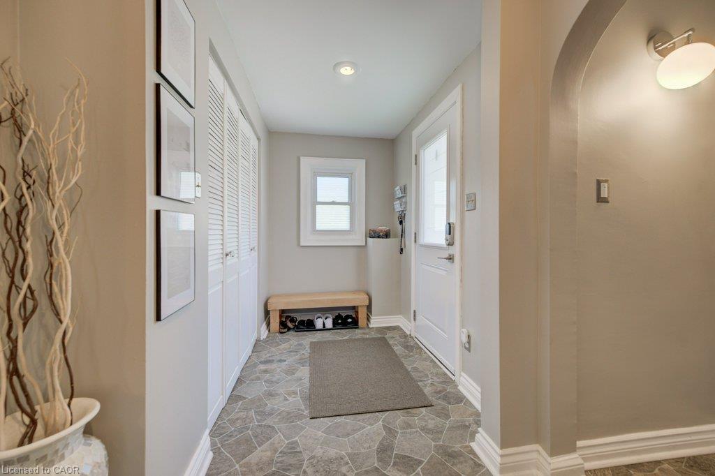 Entryway featuring stone-look flooring, a white paneled door with frosted glass insert, and a white louvered bifold closet