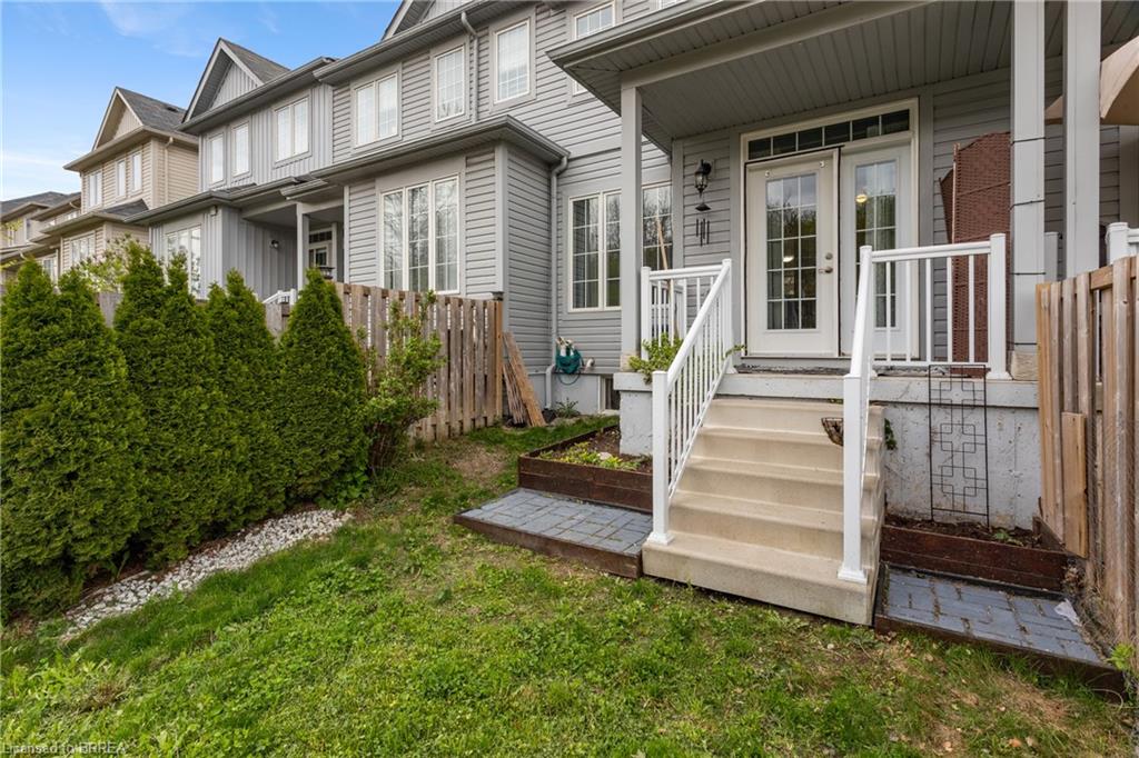 Rear exterior featuring a covered porch with white railings, glass-paned double doors, and an exterior light fixture