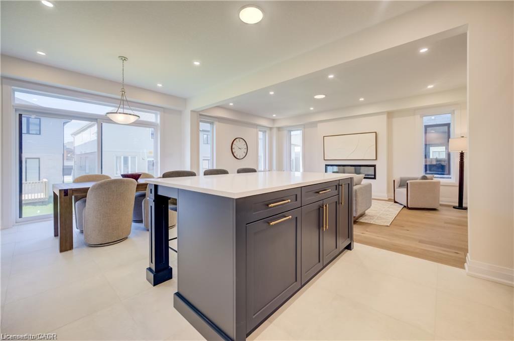 Spacious open-concept layout featuring a kitchen island with storage and seating, wood-finish flooring, a linear fireplace, and large sliding glass doors
