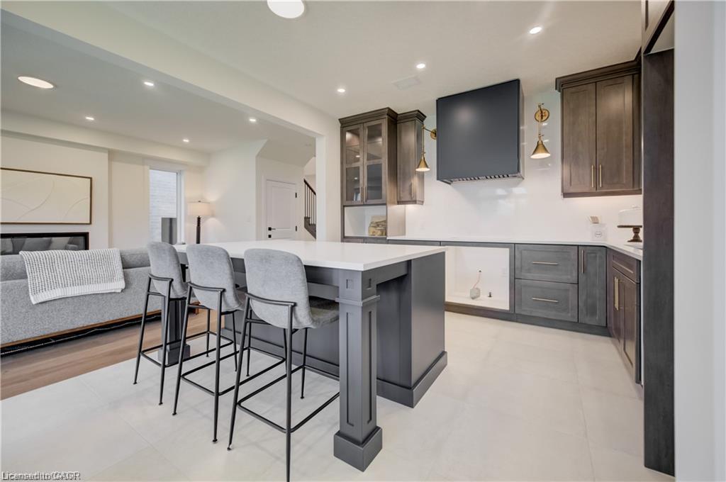 Spacious kitchen with a central island, dark wood-finish cabinetry, bright white countertops, recessed lighting, and a contemporary range hood