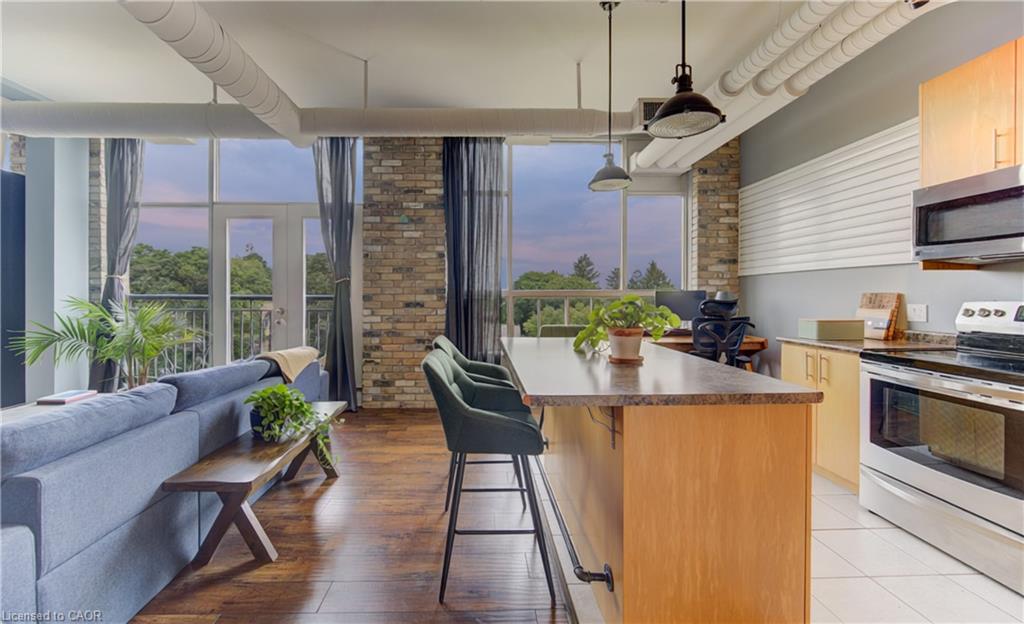 Open-concept living space featuring wood-finish flooring, exposed brick accents, and industrial-style pendant lighting