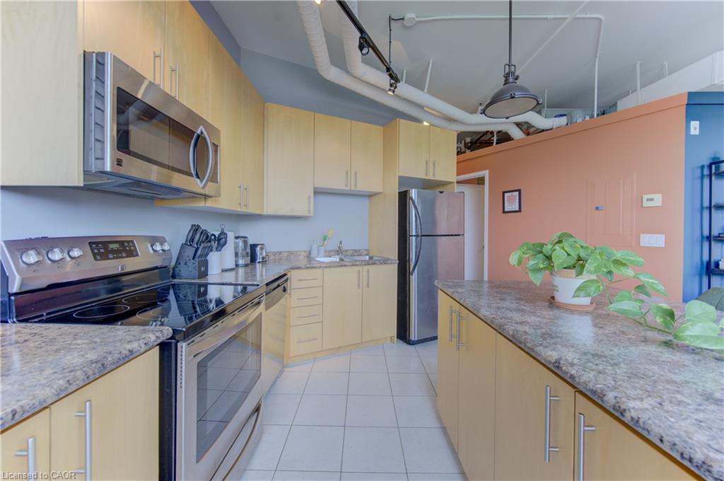 Kitchen featuring stainless steel appliances, light wood-finish cabinetry, and granite-style countertops