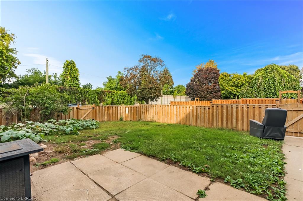 Expansive backyard featuring a wood privacy fence, concrete patio, and garden area
