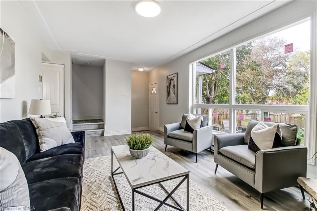 Large picture window, wood-finish flooring, recessed ceiling lighting, light-toned walls, and a modern ceiling fixture