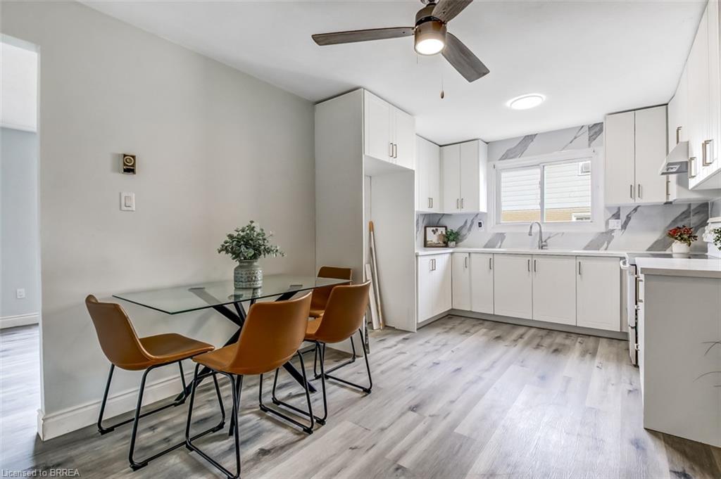 Kitchen featuring white cabinetry, gray veined backsplash, stainless steel sink, and wood-finish flooring