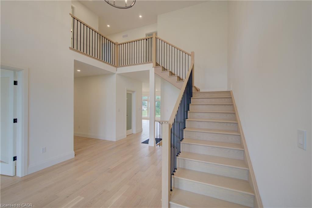 Two-story foyer featuring light wood-finish flooring, a grand staircase with dark metal balusters, and a second-story open-concept landing with matching railing