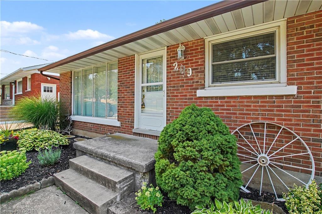 Brick exterior with white window trim, concrete front steps, and a landscaped garden bed